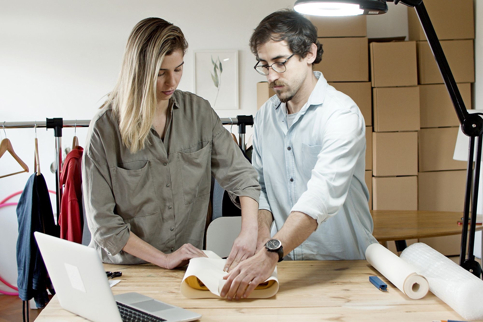 Two colleagues packing an item at a work table